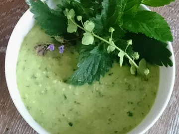 Grünes Püree in Schüssel, mit frischen Kräutern garniert.