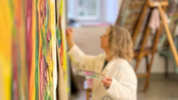 A painter is working on a colorful painting in a studio.