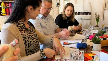 Three people are tinkering with materials at a table.