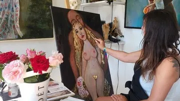 Künstlerin malt eine nackte Figur in einem Atelier.