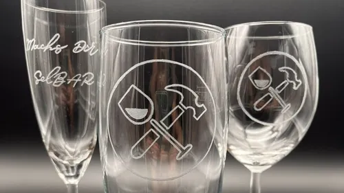 Glasses with engraved symbols and lettering stand together.