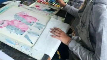 A person paints colorful parrots with watercolors.
