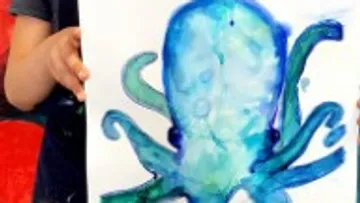 Ein Kind hält ein gemaltes Bild eines blauen Oktopus.
