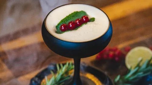 Black cocktail glass with decorative drink and berries.