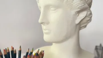Bust looks ahead, surrounded by colorful pencils.