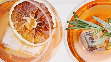 Cocktails with ice, lemon and rosemary on a table.