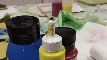 Farbflaschen stehen bereit auf einem unordentlichen Tisch.