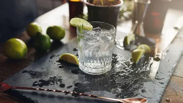 Glass with ice cubes and lime is on a table.