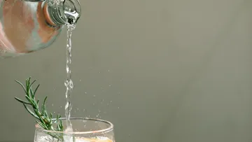 Wasser wird aus einer Flasche in ein Glas gegossen.