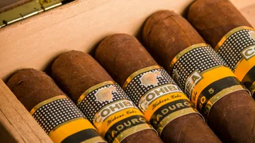 Cigars in a wooden box, neatly arranged side by side.