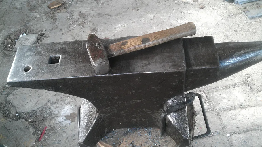 Anvil with hammer on it, in a workshop environment.