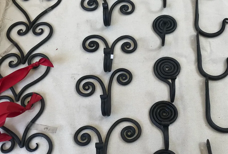 Iron hooks lie on a bright table, differently shaped.