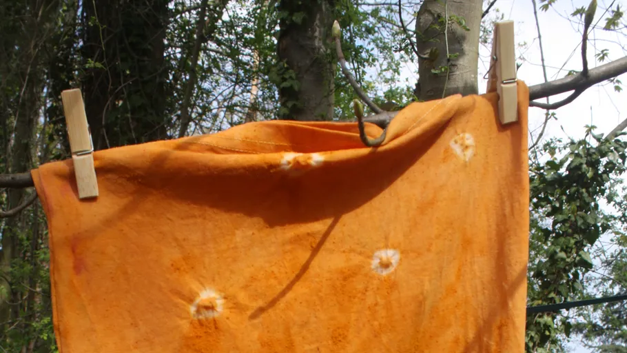 Orangefarbener Batikstoff, der draußen auf der Wäscheleine trocknet.