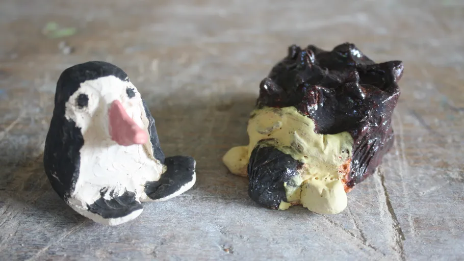 Zwei Tierfiguren aus Ton auf einer Holzoberfläche.