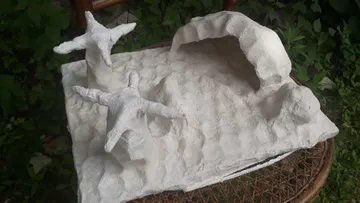 Clay sculpture of sea stars on textured surface.