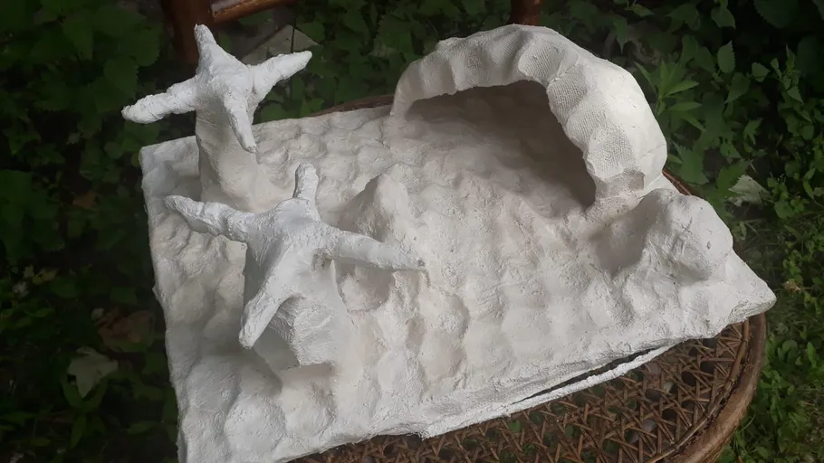 Tonskulptur von Seesternen auf strukturierter Oberfläche.