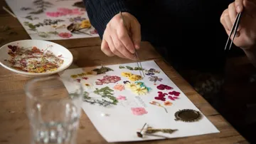 Dried flowers are carefully arranged on paper.