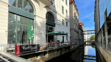 Ein Café entlang eines Kanals mit grünen Sonnenschirmen.