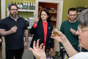 A group of people are trying olive oil in a shop.