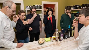 People smell olive oil in a shop.