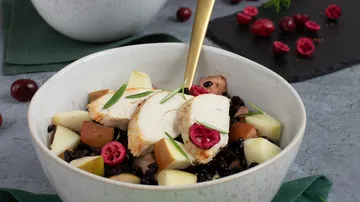 Schüssel mit Hähnchen, Früchten und schwarzem Reis, appetitlich angerichtet.