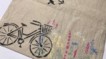 A bicycle is parked with colorful flowers in the background.