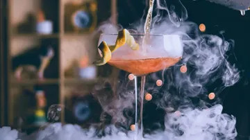 Cocktail mit rauchigem Dampf, auf einem Tisch serviert.
