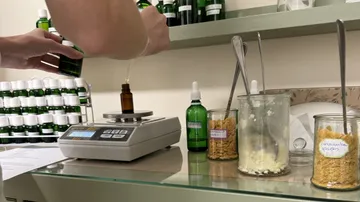 Person, die Substanzen im Labor mit grünen Flaschen wiegt.