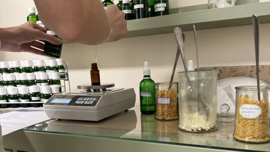 Person weighing substances in lab with green bottles.