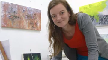 Woman smiles while working in an art studio.