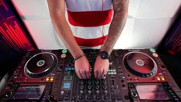DJ mixes music on a mixer, close-up of hands.