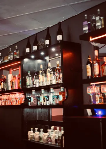 Shelf with various alcohol bottles glows in the dark.