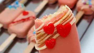 Cake on a stick with hearts, decorated and bitten.