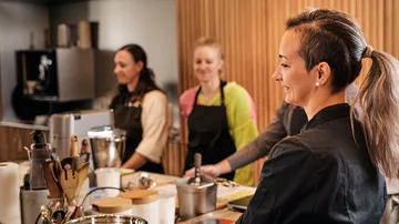 Group of women cook together in a modern kitchen.