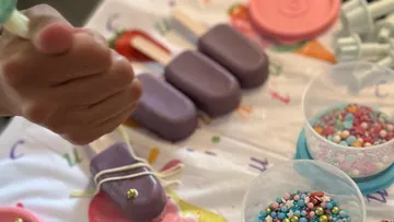 Hand decorated cakesicles surrounded by colorful sprinkles