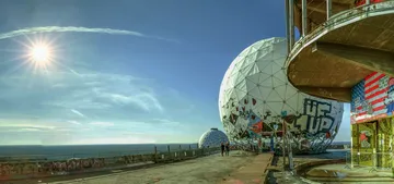 Graffiti-bedeckte Kuppeln stehen am Meer unter sonnigem Himmel.
