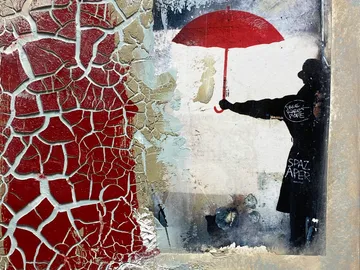 Cracked wall with red umbrella and silhouette.