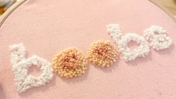 Embroidered word “boobs” on pink fabric