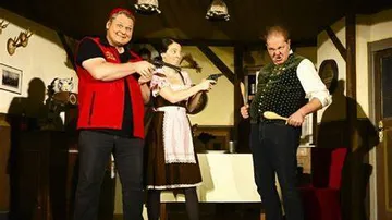 Three people in a cozy environment are holding weapons.
