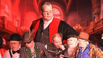 Eine Gruppe von Männern diskutiert in einem festlichen Raum.