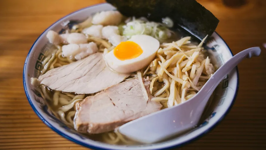 A bowl of ramen with meat, egg and vegetables.