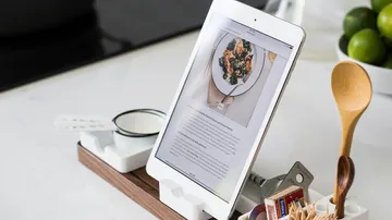 Tablet zeigt ein Rezept, umgeben von Küchengeräten und Zutaten.