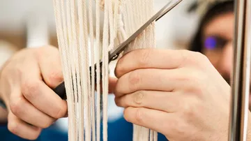 A person cuts off threads with scissors.