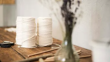 Two spools of thread lie on a wooden table surrounded by decoration.