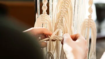 Hands knot bright cords into a wall hanging, creative