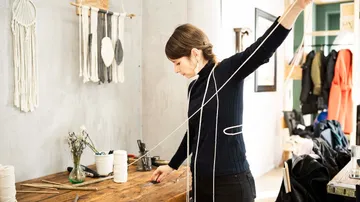 Eine Frau arbeitet an einem Holztisch mit Schnur.