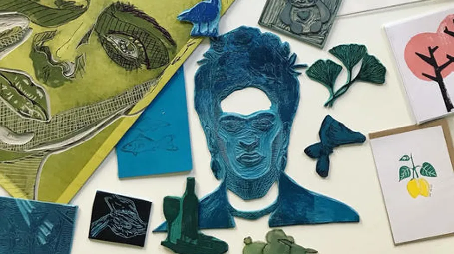 Colourful printing plates and sketches spread out on a table.