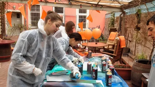 Personen sprayen Farben auf Materialien in einem Außenbereich.