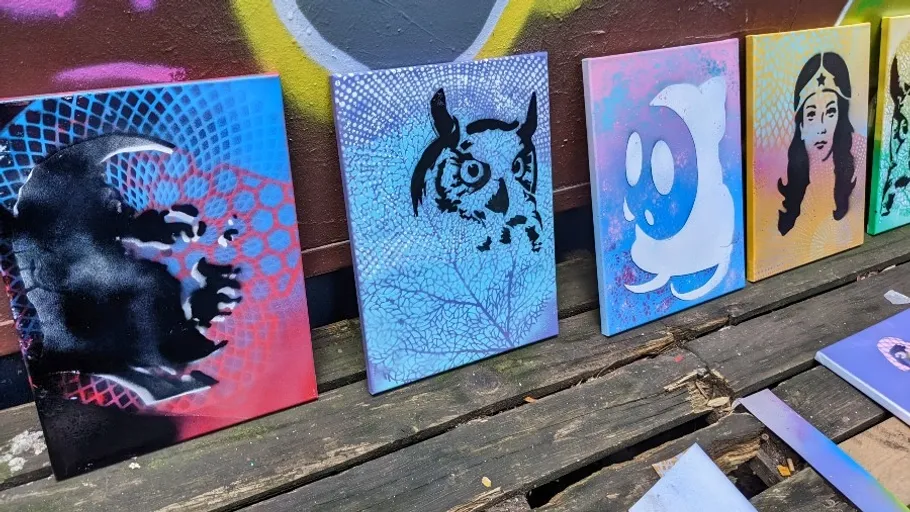 Sprühbemalte Leinwände auf Holzoberfläche im Freien.