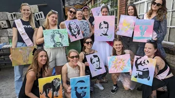 Gruppe von Frauen zeigt ihre bunten, selbstgemalten Bilder.